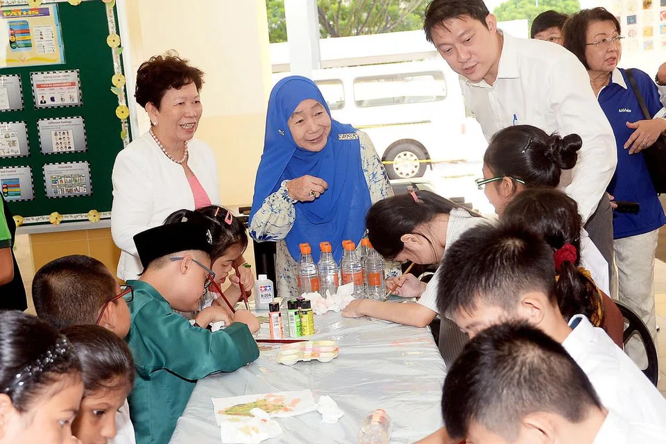 SENI MENYATUKAN MEREKA: (Dari kiri), Pengetua Sekolah Fernvale Gardens, Cik Chan Kwai Foong; Puan Noor Aishah Mohd Salim; dan Menteri Negara (Kesihatan), Dr Lam Pin Min, menyaksikan pelajar arus utama daripada Sekolah Rendah Fernvale menjalankan kegiatan seni bersama pelajar kurang upaya intelek daripada Sekolah Fernvale Gardens sempena sambutan Hari Sindrom Down Sedunia semalam. - Foto JOHARI RAHMAT