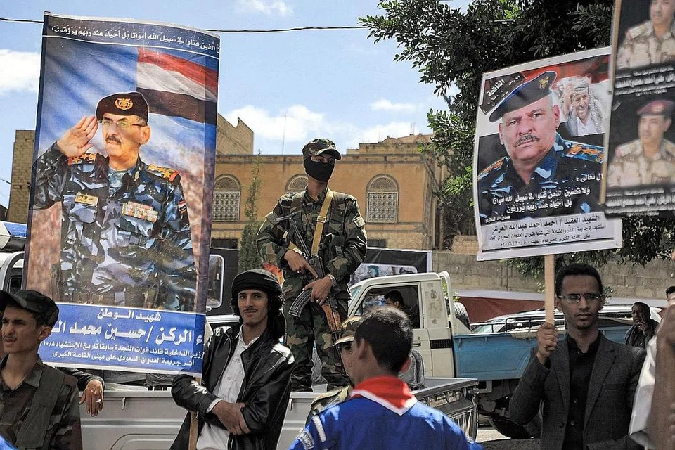 PERANG PROKSI: Pejuang yang taat kepada pemberontak Houthi Yaman berdiri di sisi sepanduk memperingati ulang tahun kelima kematian pegawai tentera yang terbunuh semasa serangan udara oleh sekutu yang dipimpin Arab Saudi, di ibu kota Sanaa, Yaman, pada 9 Oktober lalu. - Foto AFP