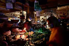 BERGELAP:(atas) Peniaga di pasar Dhaka menjual sayur-sayuran terpaksa menggunakan lilin akibat krisis bekalan elektrik di Bangladesh. Orang ramai berjalan dalam keadaan gelap - Foto-foto AFP