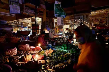 BERGELAP:(atas) Peniaga di pasar Dhaka menjual sayur-sayuran terpaksa menggunakan lilin akibat krisis bekalan elektrik di Bangladesh. Orang ramai berjalan dalam keadaan gelap - Foto-foto AFP