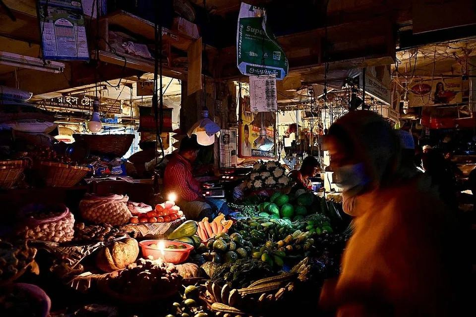 BERGELAP:(atas) Peniaga di pasar Dhaka menjual sayur-sayuran terpaksa menggunakan lilin akibat krisis bekalan elektrik di Bangladesh. Orang ramai berjalan dalam keadaan gelap - Foto-foto AFP
