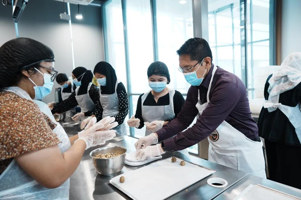 Menteri di Pejabat Perdana Menteri, Dr Mohamad Maliki Osman, yang juga Menteri Kedua (Ehwal Luar merangkap Pendidikan) (kanan) dan lebih 40 sukarelawan menyertai sesi menyediakan dan membungkus kuih-muih di Kelab Masyarakat Siglap pada 5 Mac.