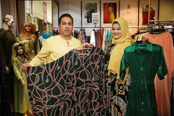 TERJEJAS: Cik Siti Rohani (kanan) berkata ramai pelangganya lebih gemar ke kedai untuk mencuba sendiri pakaian yang ditawarkan daripada membeli dalam talian. Di sisi beliau ialah suaminya, Encik Mohammad Reza Bojodi. - Foto BH oleh NAKANISHI SHOI
