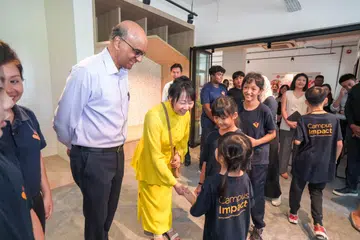 Puan Jane Ittogi (berbaju kuning) bersalaman dengan salah seorang kanak-kanak yang disokong oleh CampusImpact pada pelancaran Cabaran Presiden 2024 sambil diperhatikan Presiden Tharman Shanmugaratnam (kiri), Nur Qamarina Muhammad Rhyme (tiga dari kanan) dan Nur Syarafina Muhammad Rhyme (dua dari kanan).