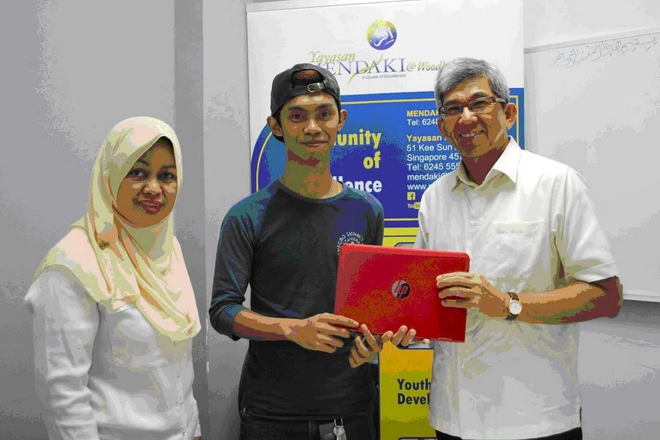 PERMUDAH PEMBELAJARAN: Dr Yaacob (kanan) menyerahkan komputer riba yang dibeli hasil sumbangan beberapa individu yang prihatin terhadap nasib Encik Ridzuan, sambil disaksikan Ketua Pegawai Eksekutif Mendaki, Cik Tuminah Sapawi. - Foto YAYASAN MENDAKI