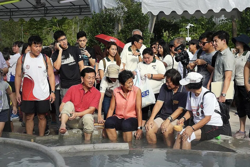 TEMPAT PERTEMUAN UNIK: Encik Ong Ye Kung (berbaju merah) merendam kaki di kolam mata air panas bersama pengunjung yang hadir ketika majlis perasmian Taman Hot Spring Sembawang semalam. - Foto BM oleh ALPHONSUS CHERN