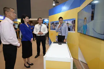 Menteri Negara (Ehwal Dalam Negeri merangkap Pembangunan Sosial dan Keluarga), Cik Sun Xueling (dua dari kiri) bersama Ketua Eksekutif Akademi Home Team (HTA), Encik Anwar Abdullah (kiri) sedang melihat pertunjukan avatar kecerdasan buatan (AI) dengan pegawai HTA (kanan) bertanya beberapa soalan kepada watak wanita dalam skrin yang menyerupai seorang mangsa satu kes rompak lari.