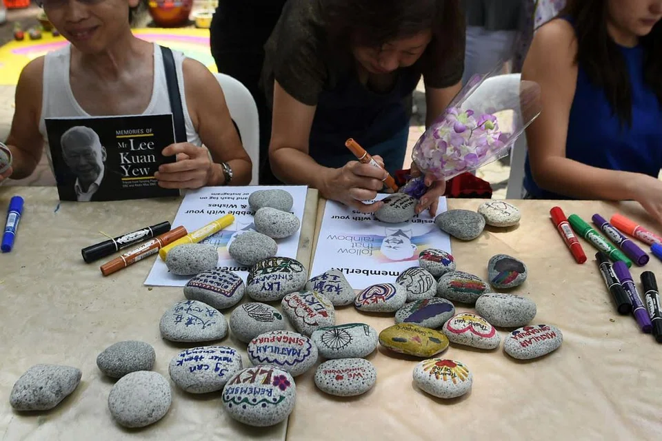 ACARA DI SERATA PULAU - PERINGATAN UNIK: Orang ramai menulis kata-kata penghargaan atas sumbangan Encik Lee Kuan Yew di batu-batu kecil, semalam. - Foto AFP