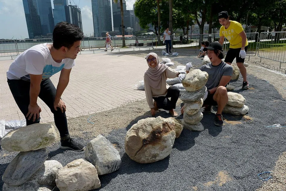 MENYUSUN 'BATU BERNYALA: Penuntut jurusan seni bina dari Politeknik Singapura, Cik Mirra Najihah Abdul Hashim (dua dari kiri), bersama anggota kumpulannya menyusun batu yang dipalit cat bernyala dalam gelap bagi seni pemasangan terra.glimmer untuk Pesta i Light Marina Bay 2016. 