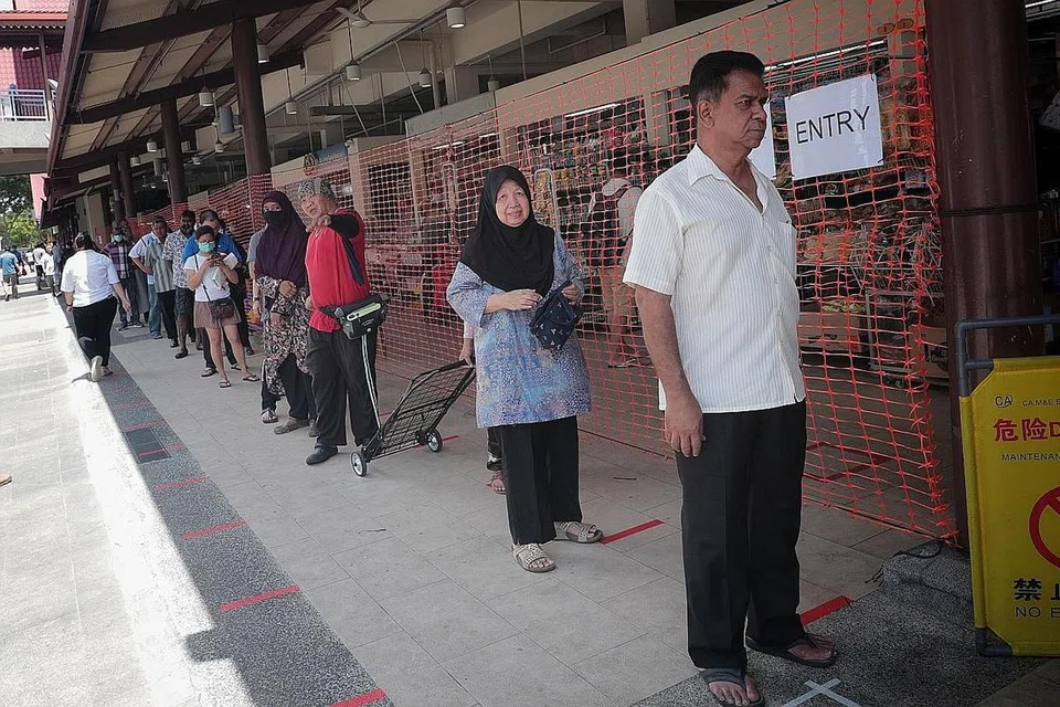 DIPERKETAT: Pengunjung ke Pasar Geylang Serai semalam perlu beratur dan menunggu giliran mereka sebelum dapat masuk ke kawasan pasar untuk berbelanja. - Foto BH oleh JASON QUAH