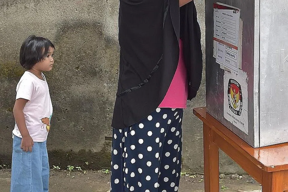 JALANKAN TANGGUNGJAWAB: Seorang penduduk setempat membuang undi di Tangerang, Banten, semalam. - Foto AFP