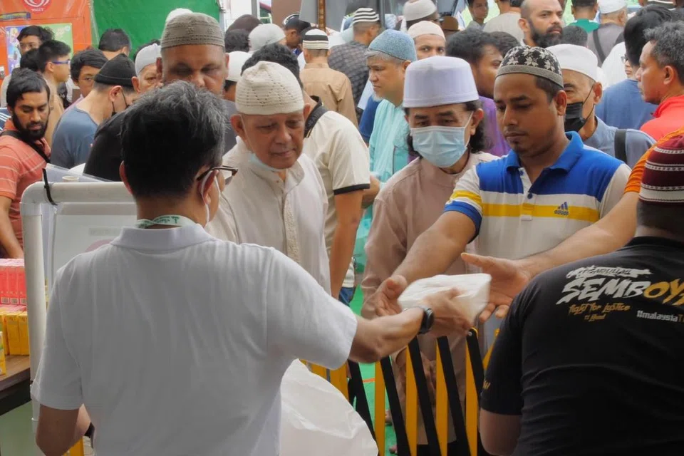 Encik Nassir (membelakangi kamera) menguruskan sumbangan makanan dan minuman kepada jemaah solat Jumaat di Masjid Alkaff Kampung Melayu. 