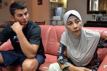 SOKONGAN KELUARGA: Encik Dino mencari saluran bagi membolehkan ibu Cik Eny mendapatkan rawatan segera di NNI, malah menyiapkan kertas latihan hampir setiap malam sebagai 'kerja rumah' ibunya semasa Encik Dino keluar bertugas. - Foto M.O. SALLEH