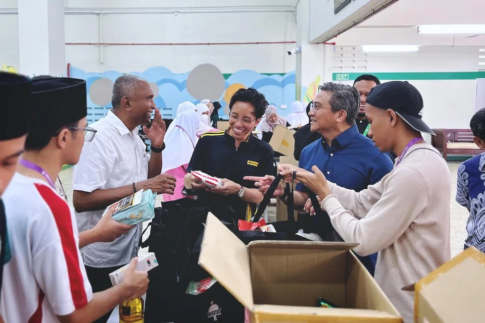 Presiden Pertapis, Encik Mohamed Shaharin Mohamed Nordin (dua dari kiri) kelihatan membungkus habuan bersama Anggota Parlimen (AP) GRC Bishan-Toa Payoh, Encik Saktiandi Supaat (kemeja biru, dua dari kanan) dan Ketua Jabatan Perbankan Islam, Maybank Singapura, Encik Sazzali Sabandi (kemeja polo hitam).