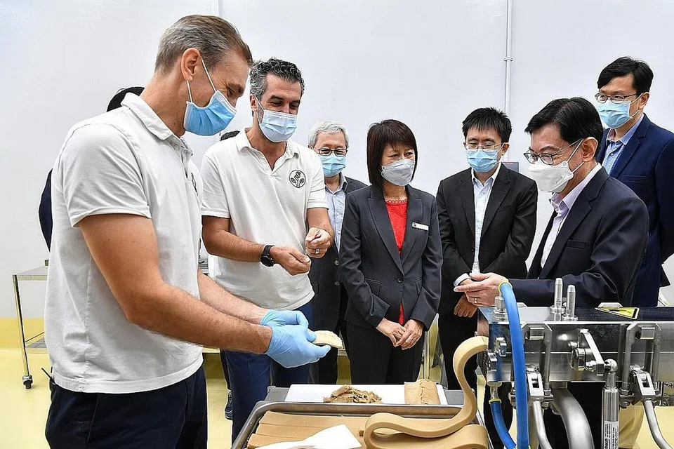 INOVASI MAKANAN: Ketua pengeluaran SGProtein, Encik Bernhard Schiele (kiri), serta CEO dan pengasas bersama SGProtein, Encik Dominique Kull (dua dari kiri), menunjukkan kepada Encik Heng Swee Keat (depan kanan) cara mesin penyemperitan berfungsi semasa pelancaran kilang FoodPlant semalam. - Foto BH oleh CHONG JUN LIANG