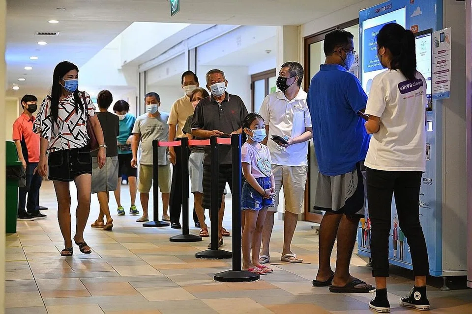 PELITUP PERCUMA: Orang ramai kelihatan beratur mendapatkan pelitup percuma dari mesin layan diri di Kelab Masyarakat Hougang. Agihan pelitup percuma itu dibiayai Yayasan Temasek. - Foto fail