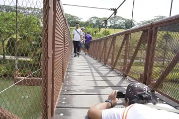 TEKNIK PENTING: Pelajar ITE ini dengan bersungguh-sungguh meniarap di atas jembatan dekat Punggol Waterway untuk mendapatkan sudut gambar paling menarik dengan hanya menggunakan telefon bimbit. - Foto-foto TEMASEK