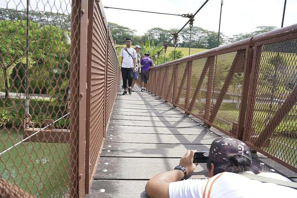 TEKNIK PENTING: Pelajar ITE ini dengan bersungguh-sungguh meniarap di atas jembatan dekat Punggol Waterway untuk mendapatkan sudut gambar paling menarik dengan hanya menggunakan telefon bimbit. - Foto-foto TEMASEK