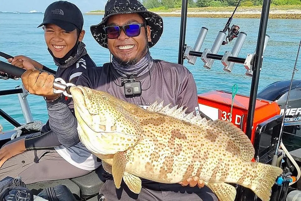 KERAPU!: Seorang pelanggan Get Hooked SG mempamerkan tangkapan ikan kerapu yang memakan umpannya ketika berada di perairan Tuas.