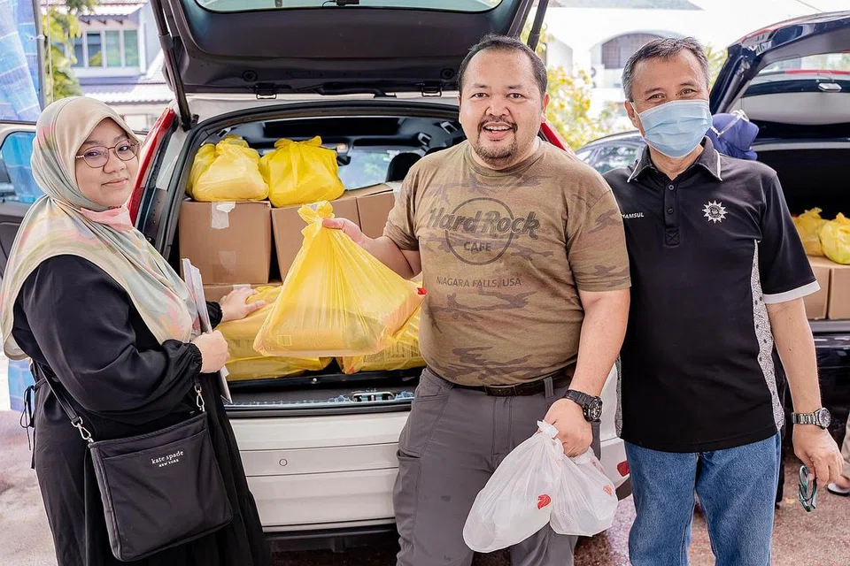 HULUR BANTUAN : (Dari kiri) Cik Norazni Alaiha, 40 tahun, dan suami, Encik Musa Mohamad Sair, 46 tahun, bersama eksekutif kanan jabatan kebajikan Persatuan Muhammadiyah, Encik Shamsul Bahri Talib, menyingsing lengan untuk mengagihkan habuan makanan termasuk beras, makanan kering dan barang keperluan rumah lain kepada keluarga berpendapatan rendah di Bedok Reservoir dan Beach Road sempena Ramadan.