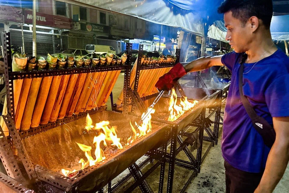 Seorang peniaga lemang di Johor Bahru, Encik Shahir Abd Kata meratakan bara api arang bagi memastikan lemang yang dibakar dapat dimasak pada suhu yang sekata.