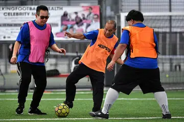 SUKAN DEMI KESIHATAN: Encik Hamdi (tengah) menahan bola sebelum menendangnya kepada rakan pasukan. Beliau diperhatikan oleh pihak lawannya, Cef Amri (kiri), yang turut menyokong usaha Walking Football4Health. - Foto BH oleh LIM YAOHUI