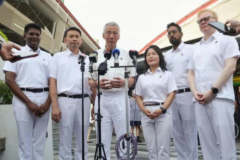 Encik Lee Hsien Loong (tiga dari kiri), diapit calon Parti Tindakan Rakyat (PAP) bagi GRC Aljunied, (dari kiri) Encik Jagathishwaran Rajo, Encik Adrian Ang, Cik Chan Hui Yuh, Dr Faisal Abdul Aziz dan Encik Daniel Liu, di Pasar dan Pusat Makanan Blok 630, Bedok Reservoir Road, pada 29 April.