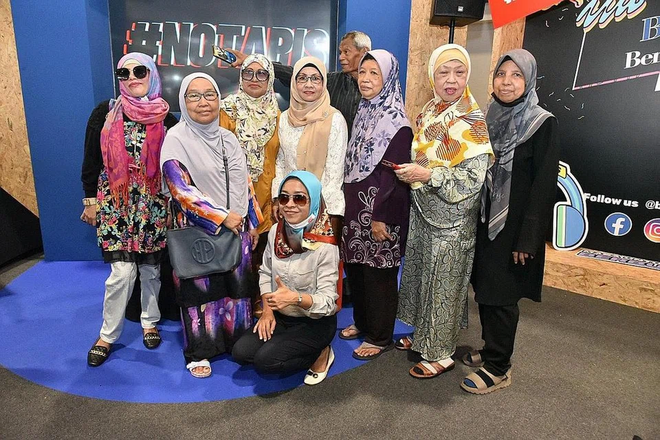 BIDUANITA LEGENDA: Sanisah Huri (empat dari kiri) menyerikan gerai BHazar Berita Harian di Anjung@Wisma Geylang Serai dengan dendangan lagu-lagu Hari Raya yang telah menarik ramai peminat. - Foto BH oleh M.O. SALLEH