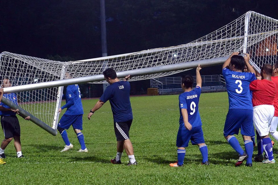 GOTONG-ROYONG: (Atas) Pemain bola sepak CP bekerjasama mengangkat gawang khas yang kini digunakan dalam latihan dan perlawanan. 