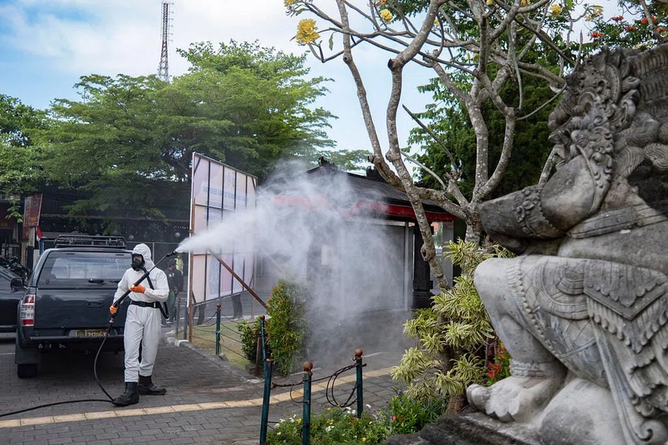 BASMI KUMAN: Seorang pekerja sedang melakukan tugas menyahjangkit satu taman di Denpasar, Bali. Pulau itu, bersama Pulau Jawa, mencatat jumlah kes aktif tertinggi di Indonesia. - Foto EPA-EFE