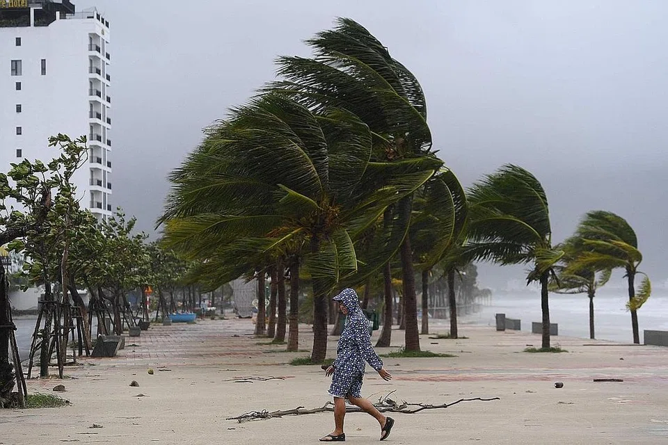ANGIN KENCANG: Seorang lelaki dilihat meredah angin kuat di tepi pantai Danang, semalam.