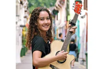 DEKATI BELIA: Petikan gitar pemuzik muda Mariam Bamadhaj telah memberinya peluang mendekati belia kurang bernasib baik ketika beliau menjalani latihan amali sebagai penyelaras projek belia di Persatuan Masyarakat Castlehaven di kawasan Camden, London. - Foto KHALID BABA