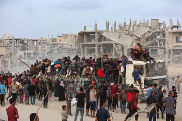Penduduk Palestin menaiki bahagian belakang sebuah trak di laluan pantai barat Beit Lahia selepas berjaya mendapatkan bungkusan bantuan pada 29 Julai 2025, selepas beberapa trak bantuan berjaya memasuki Jaluran Gaza yang dikepung Israel melalui lintasan sempadan utara Zikim