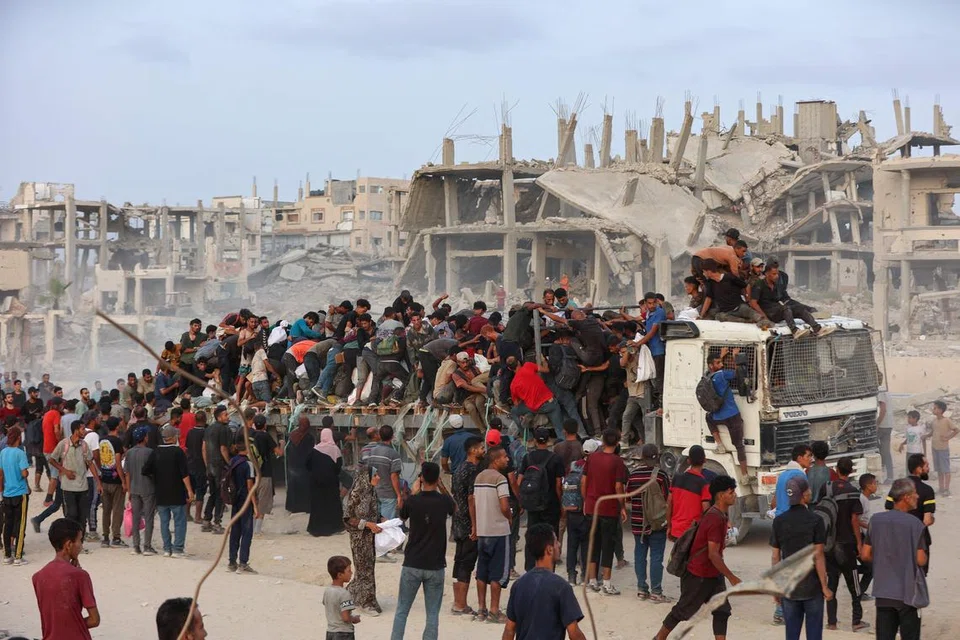 Penduduk Palestin menaiki bahagian belakang sebuah trak di laluan pantai barat Beit Lahia selepas berjaya mendapatkan bungkusan bantuan pada 29 Julai 2025, selepas beberapa trak bantuan berjaya memasuki Jaluran Gaza yang dikepung Israel melalui lintasan sempadan utara Zikim