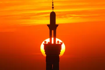 Pancaran suria di balik menara masjid yang menakjubkan dan membawa pelbagai perasaan dan kerinduan (gambar hiasan).