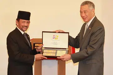 WANG PERERAT HUBUNGAN: Sultan Hassanal Bolkiah (kiri) dan Perdana Menteri Lee melancarkan wang kertas peringatan $50 Singapura dan $50 Brunei. Ia dilancarkan sempena Perjanjian Pertukaran Mata Wang Singapura-Brunei yang ke-50. - Foto ZAOBAO 
