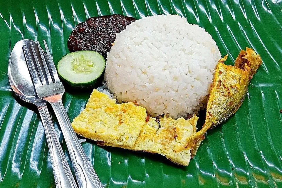MEMADAI UNTUK SARAPAN PAGI: Nasi lemak $1 sepiring atau sebungkus ini disertakan dengan nasi, seekor ikan selar kuning, dua potong kecil telur dadar, sehiris timun dan sambal 'power'; sementara versi serba lengkap yang termasuk ayam goreng pula dijual dengan harga $3.- Foto BM oleh SAINI SALLEH