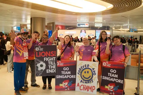 Sukarelawan Team Nila, turut menjemput kepulangan pemain bola sepak negara di Lapangan Terbang Changi pada 19 November. Berada dalam gambar ialah Cik Suzanna Gunawi, (tiga dari kanan). 