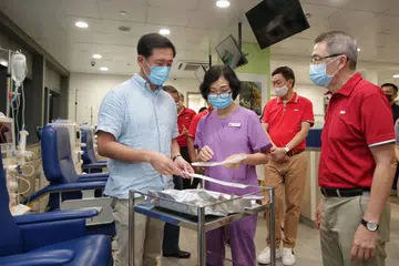LAWAT PUSAT DIALISIS: Encik Ong Ye Kung (kiri) melihat jarum dialisis yang ditunjukkan Pengurus Jururawat NKF, Cik Pan Mei Yu, semasa lawatannya ke Pusat Dialisis NKF di Hospital Masyarakat Yishun semalam. Bersama mereka ialah CEO Keppel Corporation, Encik Loh Chin Hua (dua dari kanan) dan CEO NKF, Encik Tim Oei (kanan). - Foto BH oleh GIN TAY