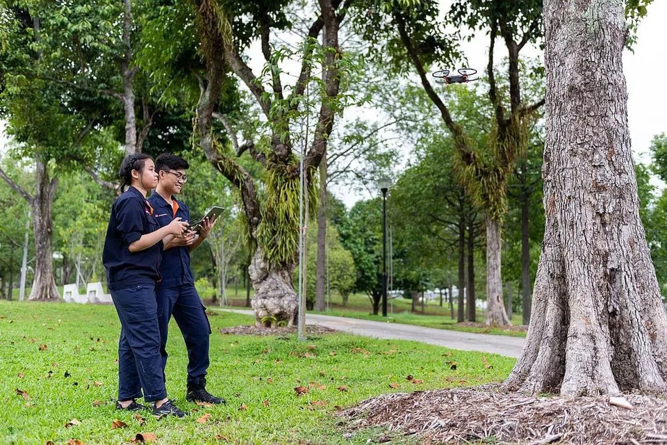 BERPELUANG GUNA TEKNOLOGI: Encik Abu Bakar (kanan) teruja diberi peluang menggunakan teknologi tinggi seperti dron untuk memeriksa keadaan pokok dalam projek perintis hasil kerjasama NParks dan ITE. - Foto ITE