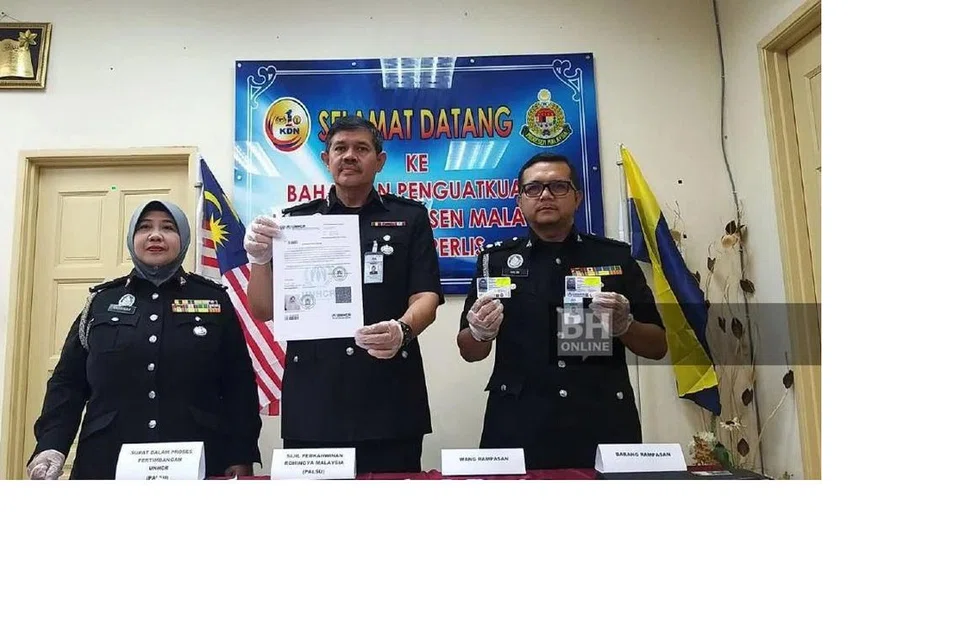 SINDIKET NIKAH ROHINGYA: Pengarah Imigresen Perlis, Encik Khairul Amin Talib (tengah), menunjukkan surat palsu UNHCR yang dirampas di sebuah madrasah di Kangar.