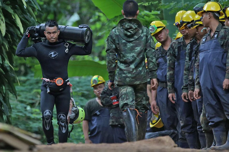 KERAH SEGENAP TENAGA: Penyelam meninggalkan kawasan gua sejenak sambil mengangkat tangki udara semalam. - Foto REUTERS