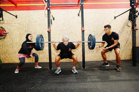 Encik Jumahat (tengah) ankat biasa (deadlift) seberat 60 kilogram dan anak-anaknya menyokong berat dari tepi.