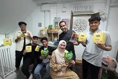 'KEDAI RUNCIT' PERCUMA: Encik Fariq (tengah, di belakang) bersama isteri, Cik Norhasyimah dan anak-anak mereka (dari kiri) Muhammad Nabil Putra, Hilman Aqil Zulikram Putra, Irfan Danial Putra dan Hamzah Lutfil Putra, di ruang infak di depan flat mereka di Tampines. - Foto BH oleh ALPHONSUS CHERN 