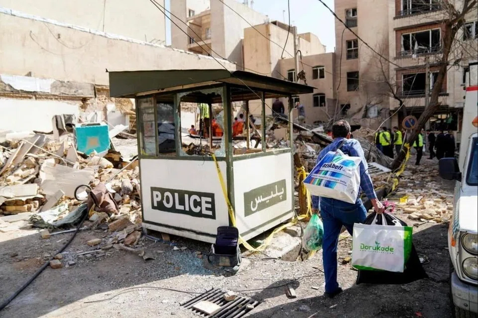 Seorang lelaki Iran membawa beg sambil melalui runtuhan bangunan yang musnah akibat serangan peluru berpandu di Tehran, pada 28 Februari.