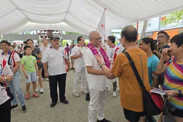 Encik Masagos Zulkifli Masagos Mohamad (dengan kalungan bunga) bertemu penduduk di Tampines Street 81 untuk mengucapkan terima kasih atas sokongan mereka.