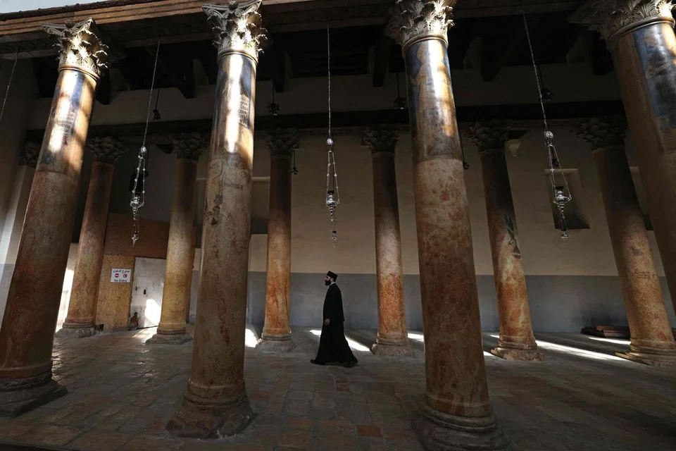 Seorang paderi melangkah masuk ke Gereja Nativity di bandar Bethlehem, Tebing Barat yang diduduki, pada 17 Disember. Di Dataran Manger Bethlehem, hiasan Krismas hampir tiada buat tahun kedua berturut-turut semasa musim perayaan dalam keadaan perang.