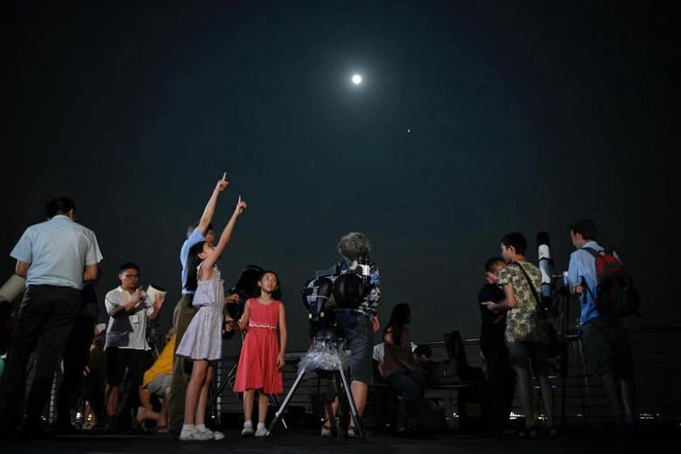 GERHANA BULAN PENUH: Orang ramai menggunakan teleskop yang disediakan di bumbung Galeri Maritim Singapura untuk menyaksikan fenomena gerhana bulan penuh semasa satu acara anjuran MPA dan SingAstro.