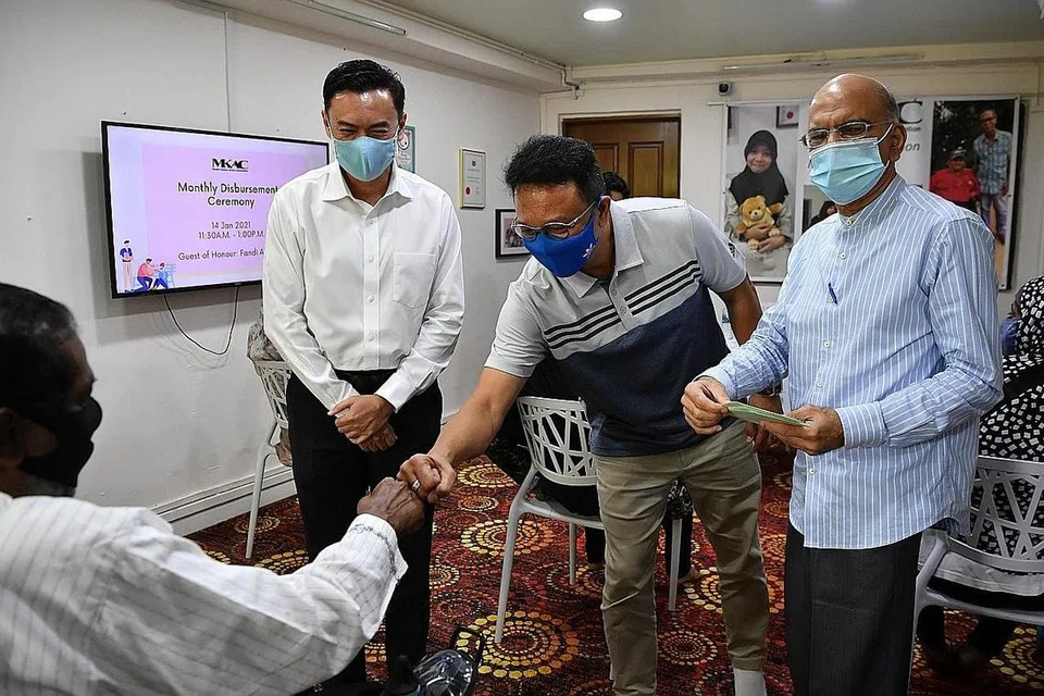 SAMPAIKAN DANA ZAKAT: (Dari kiri) Dr Wan Rizal Wan Zakariah, Fandi Ahmad dan Encik Ameerali Abdeali menyampaikan dana zakat bernilai $100 kepada seorang penerima sewaktu majlis yang diadakan di ibu pejabat MKAC semalam. - Foto BH oleh CHONG JUN LIANG