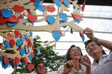 KOMITMEN SEORANG BAPA: Encik Heng Swee Keat dan isterinya, Cik Chang Hwee Nee, menulis mesej pada helaian kertas yang kemudian diikat pada 'Pokok Perjanjian' semasa perasmian acara 'Dad's Day Out 2019' di OCBC Square Hab Sukan Singapura semalam. Golongan bapa boleh menulis janji kepada keluarga sementara pihak isteri dan anak menulis nota penghargaan kepadanya. - Foto BH oleh MARK CHEONG